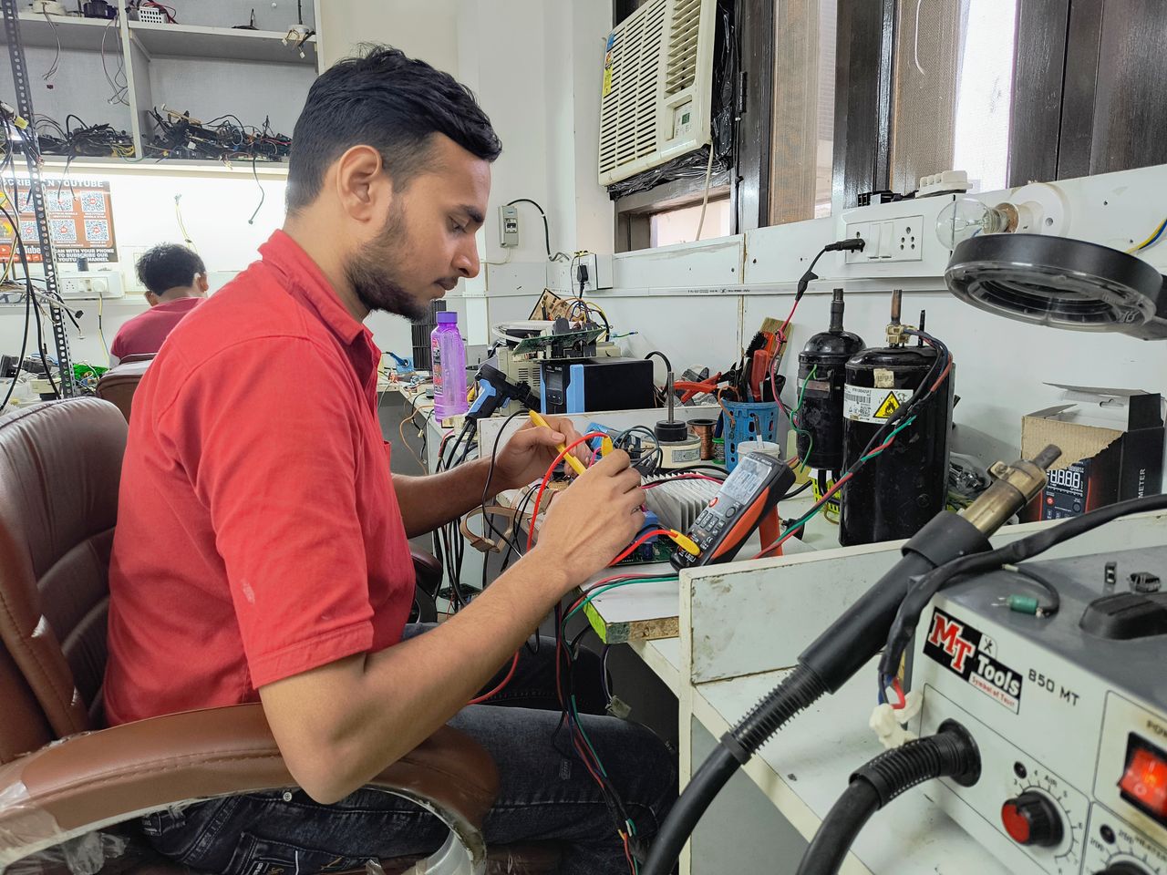 about-02 A young technician repairing electronics at a workshop. Focus on concentration and skill.
