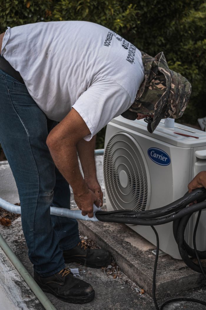 about-img A technician performs maintenance on an outdoor air conditioning unit, focusing on hose connections.