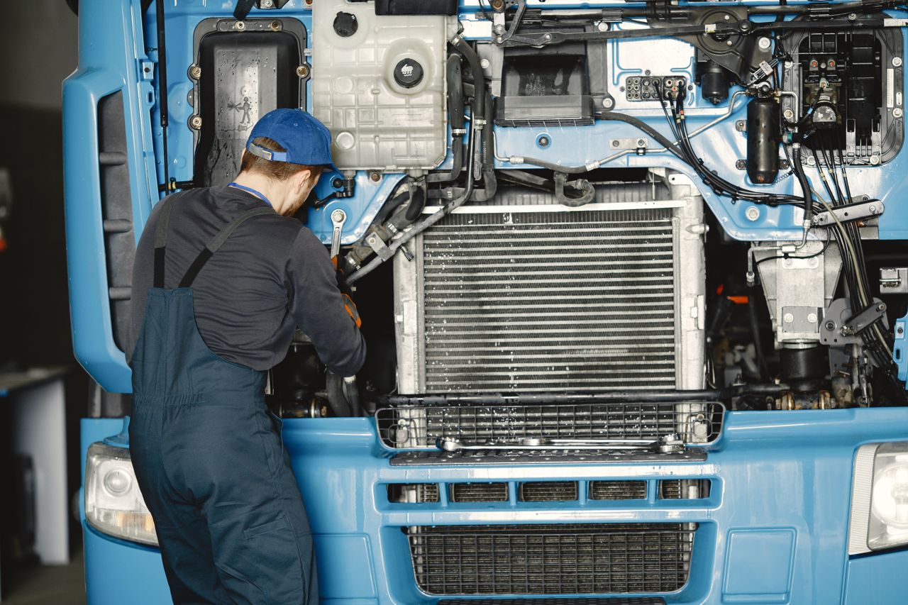 services-01 Mechanic in uniform working on a truck engine in an industrial workshop. Perfect for automotive maintenance themes.